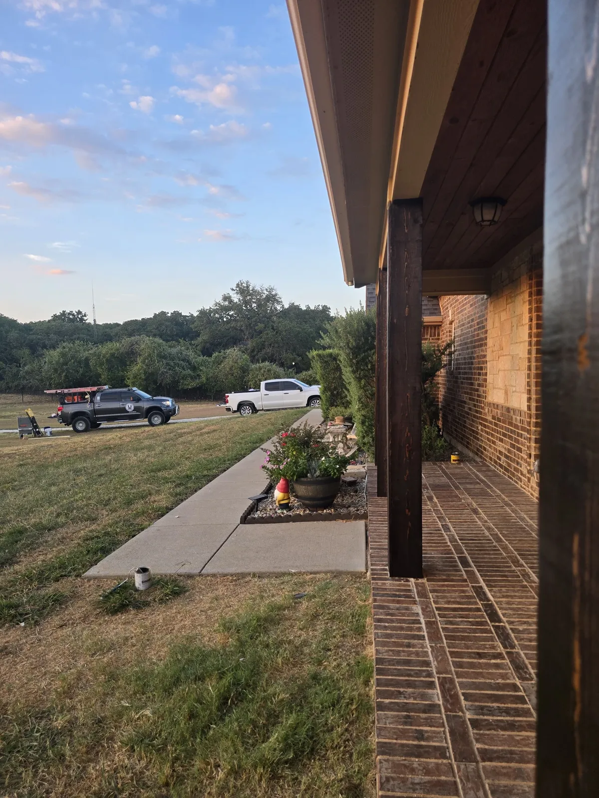 Cedar-wrapped porch posts with fresh stain along the brick porch